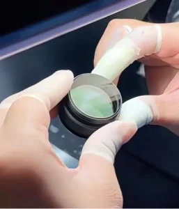 Gloved hands holding an optical lens